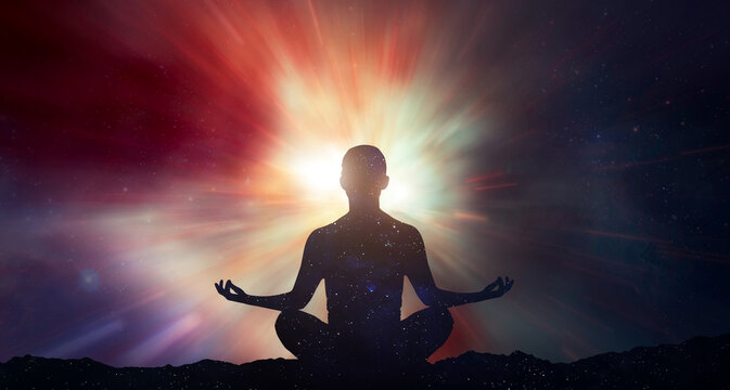 Silhouette of human in yoga lotus pose with trail lights. Galaxy and space with stars. Meditation and astrology. Esoterica and psychology. Elements of this image furnished by NASA