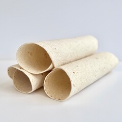 Stack of rolled flour tortillas isolated on white background, plain soft wraps with smooth surface texture in a clean minimal food composition.