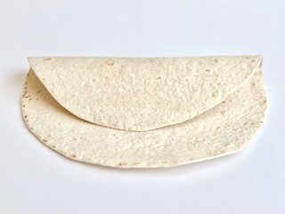 Stacked plain flour tortillas isolated on white background, soft round flatbreads folded and layered, simple food composition with clean minimal presentation.