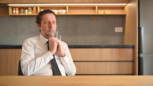 Thoughtful businessman in home office, pleading hands in deep contemplation, 4K