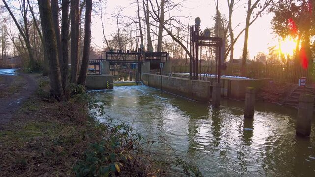 Schwenk &uuml;ber ein Wehr und weiter im Winter bei Sonnenuntergang