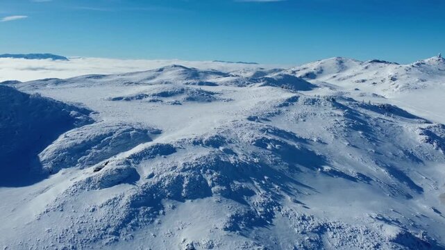 Vast snow-covered mountain plateau landscape under ble sky