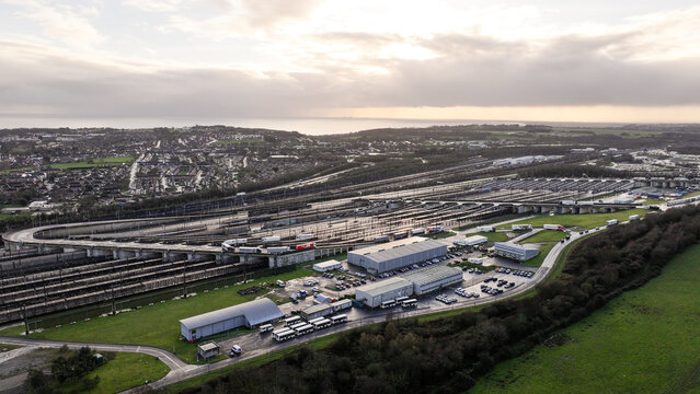 Aerial view of rail tracks stretching towards the horizon under a soft, diffused light, contrasting with the dark, industrial buildings, Folkestone, England, United Kingdom.