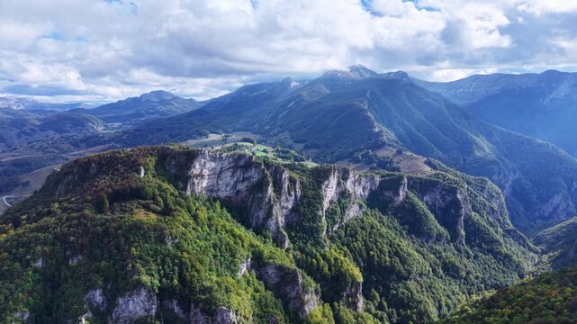 Aerial view of massive limestone cliffs rising above reen mountain forest