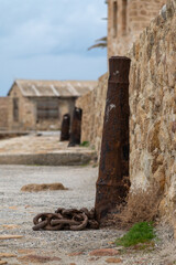 Rusted mooring cannon with iron chain along historic harbor wall in Chania, Crete