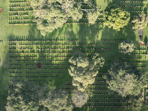 Aerial view of rows of gravesites casting long shadows across the lush green landscape, blending solemnity with the vibrant life of nature, Nairobi, Nairobi, Kenya.