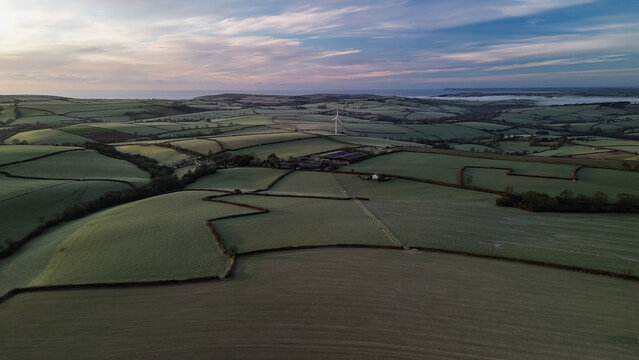 Aerial view of wind turbine over frosty rural farmland at sunrise