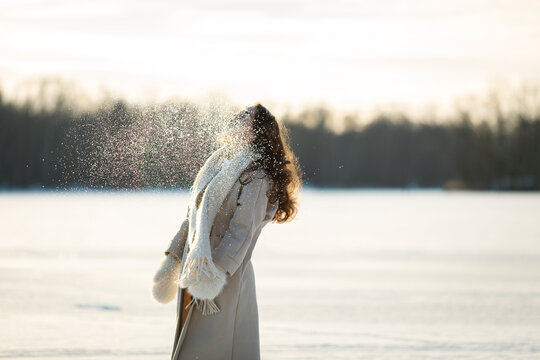 Eine Frau mit langen Haaren spielt mit dem Schnee