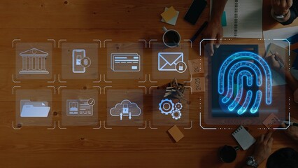 A modern workspace showcasing digital security concepts with fingerprint technology, icons for banking, communication, and data storage on a wooden table surface. Raster