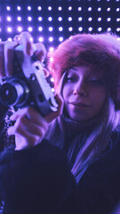 A beautiful woman photographer taking photos with a vintage camera by the neon lights at night