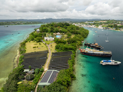 Aerial view of Iririki Island's vibrant greenery contrasts with the azure waters, solar panels gleam under the sun, and ships rest peacefully in the harbor, Port Vila, Shefa Province, Vanuatu.