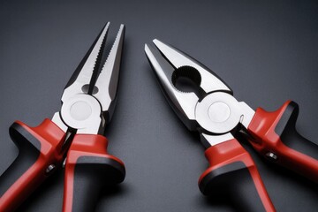 Pair of red and black handled pliers on gray background