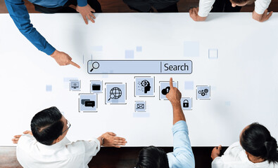 Professionals collaborate over a white table, engaging in a digital search concept with various icons symbolizing information and communication, showcasing teamwork and innovation. Trope