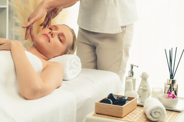 Caucasian woman enjoying relaxing anti-stress head massage and pampering facial beauty skin recreation leisure in dayspa modern light ambient at luxury resort or hotel spa salon. Quiescent