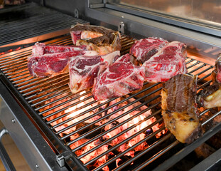 Chulet&oacute;n de ternera haci&eacute;ndose a las brasas en una cocina