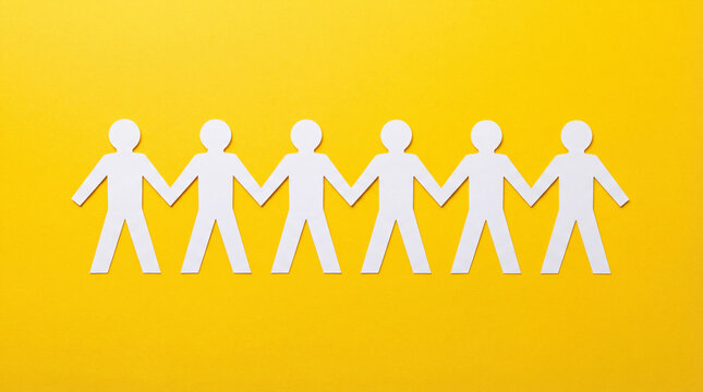 Paper People Chain on Yellow Background: White paper cutout figures holding hands, symbolizing unity, teamwork, diversity, and social connection.
