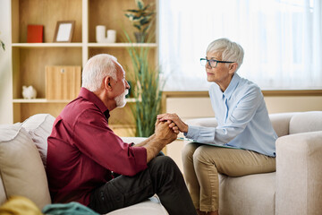 Portrait of a senior mature or mid aged man looking thoughtful or stressed and sad while sitting in...