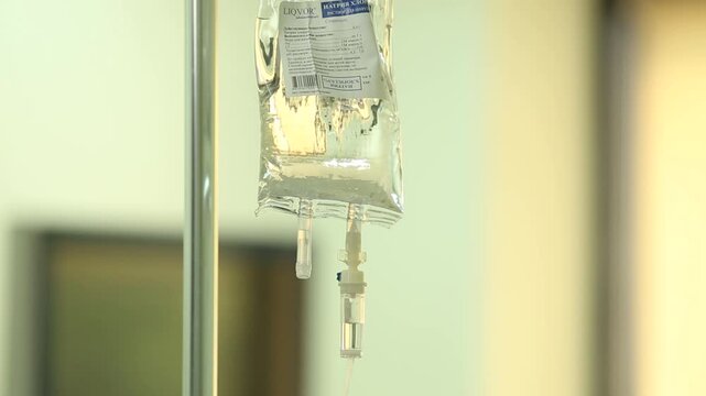 Close-up of medical intravenous infusion drip. Saline solution bag hanging on a pole in a hospital ward. Liquid medicine dripping in the chamber for patient treatment.

