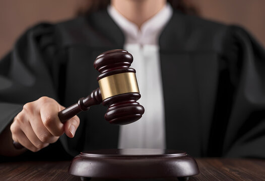 shot female judge authoritative hand holding worn wooden gavel finger poised strike metal mallet dramatic fo