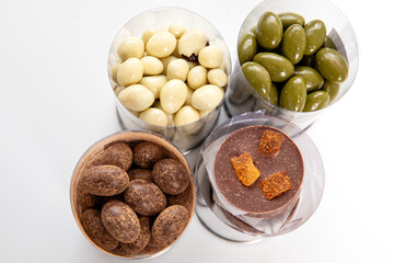 Assortment of gourmet chocolates and candied nuts in clear containers, top view