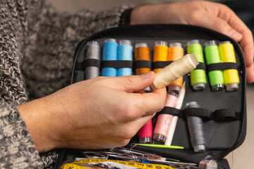 Une personne choisit sa bobine de fil à coudre dans sa trousse à couture.  © Gautier Normand