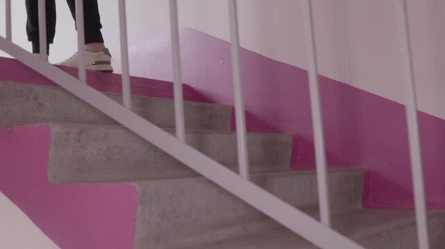 Lower half view of young caucasian woman walking upstairs in white sneakers, indoor stairway, concept of daily movement and active lifestyle.