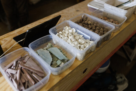 Plastic bowls containing small pieces of different kinds of rocks, used by a specialist worker who restores old terrazzo floors.