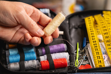 Une personne choisissant sa bobine de fil blanc pour coudre. © Gautier Normand
