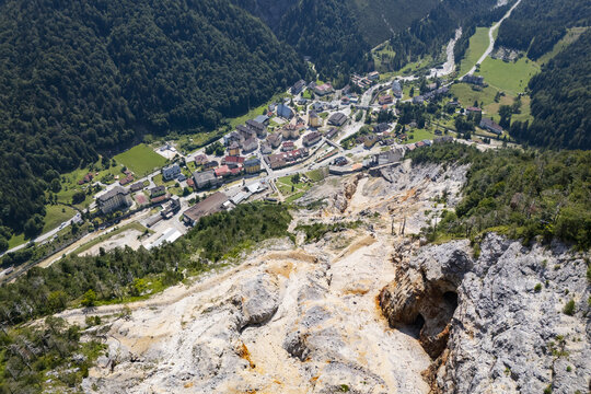 Aerial view of the town nestled between lush green mountains and a rocky landscape, creating a striking contrast of nature, Rabelj, Friuli-Venezia Giulia, Italy.