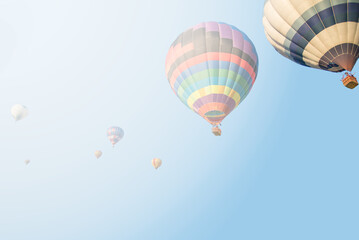 Obraz premium Vibrant Hot Air Balloons Soaring Through a Misty Blue Sky at Dawn