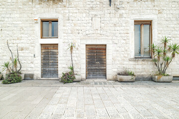 Bari, Italy. Stone facade of traditional homes along Via Venezia in Bari, with wooden doors, tall windows and potted plants, showcasing the quiet charm of historic Mediterranean architecture.