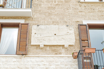 Bari, Italy. Stone facade along Via Venezia in Bari with windows and balconies, featuring a commemorative marble slab marking the Miracle of the Fire dated May 8, 2003.