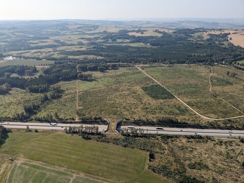 Aerial panorama of a wildlife corridor bridge allowing animals to safely cross a busy highway in Central Europe, illustrating habitat connectivity, road ecology, and biodiversity protection