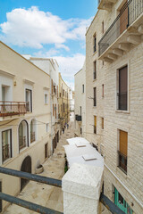 Bari, Italy. View of Vico X Corsioli from Via Venezia in Bari, with historic stone buildings and narrow alley perspective. In the distance rises the ancient Palazzo del Sedile tower.