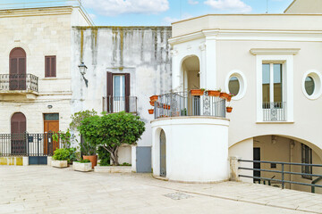 Bari, Italy. Facade of historic buildings and homes along Via Venezia in Bari, featuring light stone walls, balconies with plants and elegant details in a quiet pedestrian area.