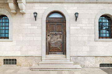 Bari, Italy. Historic stone facade along Via Venezia in Bari, featuring an arched wooden door, iron grilles and wall lamps, expressing the timeless character of the old city.