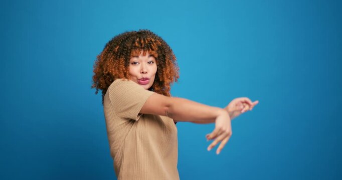 Happy, smiling hispanic woman with curly hairstyle dancing, fooling around looking at camera