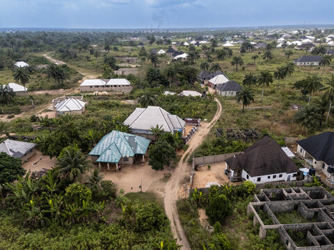 Aerial view of buildings with roofs of varying colors and textures nestled among lush green vegetation, Oboh, Rivers, Nigeria.