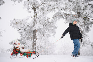 Children playing outdoors pulling sled in snowy forest