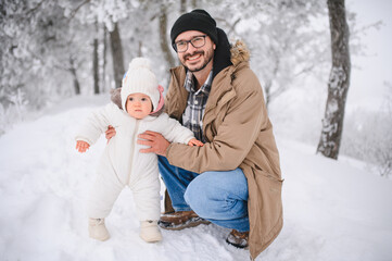 Obraz premium Happy father teaching baby walking in winter