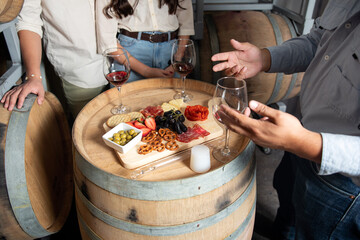 Naklejka premium Wine tasting experience with charcuterie board on barrels in a cellar