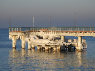 pier in the winter sea covered in icicles