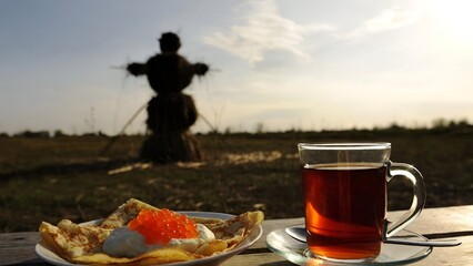 Traditional outdoor breakfast with pancakes red caviar and tea during rural festival celebration at sunrise
