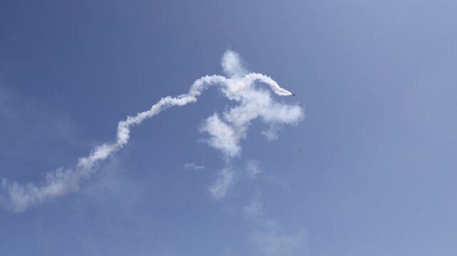 Small Sport Aircraft Creating White Vapor Patterns During Aerobatic Flight Against a Clear Blue Sky