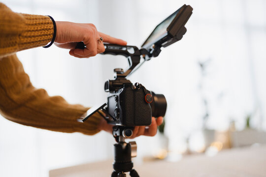 A person's hands adjust a professional camera mounted on a tripod, preparing to capture a shot.