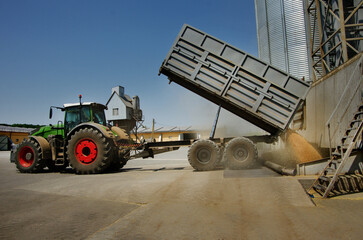 Agricultural large tractor with trailer near grain silos at elevator complex unloading grain harvest © pavlobaliukh