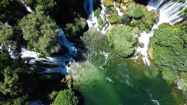 Top-down aerial view of hidden waterfall oasis in gren forest
