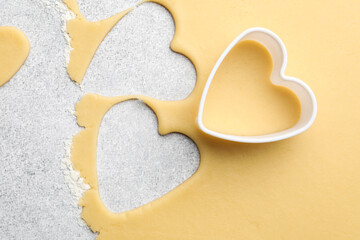Obraz premium Uncooked heart shaped cookies and raw dough on light gray table, top view