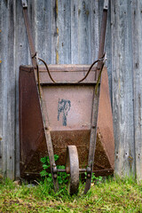 rusty wheelbarrow by the boards on a green grass day