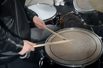 Fototapeta premium Man with drumsticks playing drum in studio, closeup